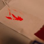 Red paint splatters on white paper