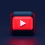 A 3D red play button icon on a dark blue background